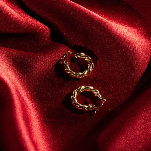 Gold jewelry against red sheet background as part of Product Pop photo shoot