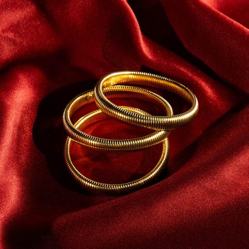 Gold bracelets against red background sheet as part of Product Pop photo shoot